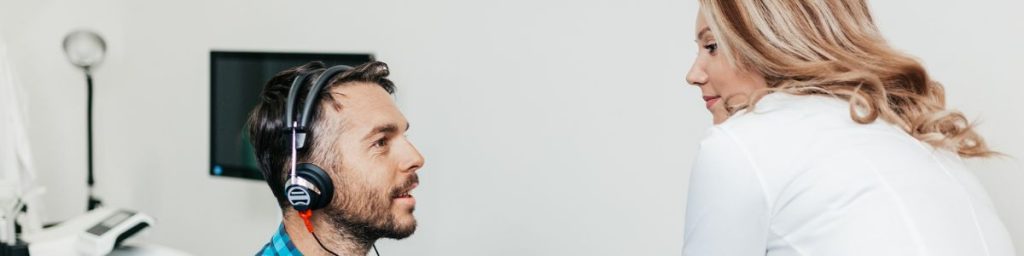 A doctor looking at patient who is wearing audiometric headphones